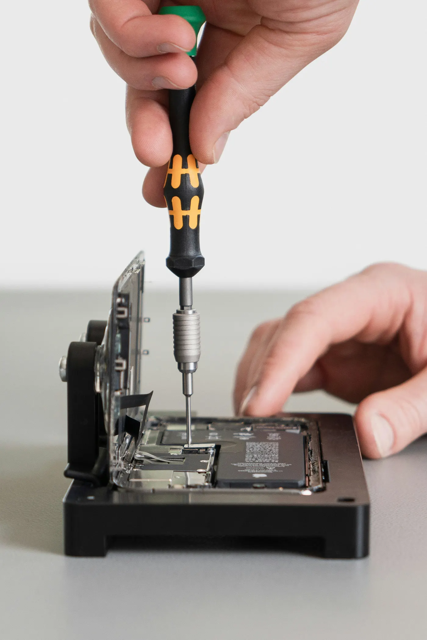 Técnico reparando um iPhone aberto com uma chave de precisão, assistência técnica especializada Apple em Curitiba